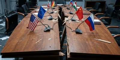 Broken conference table with national flags, symbolizing fractured international relations and failed diplomacy.